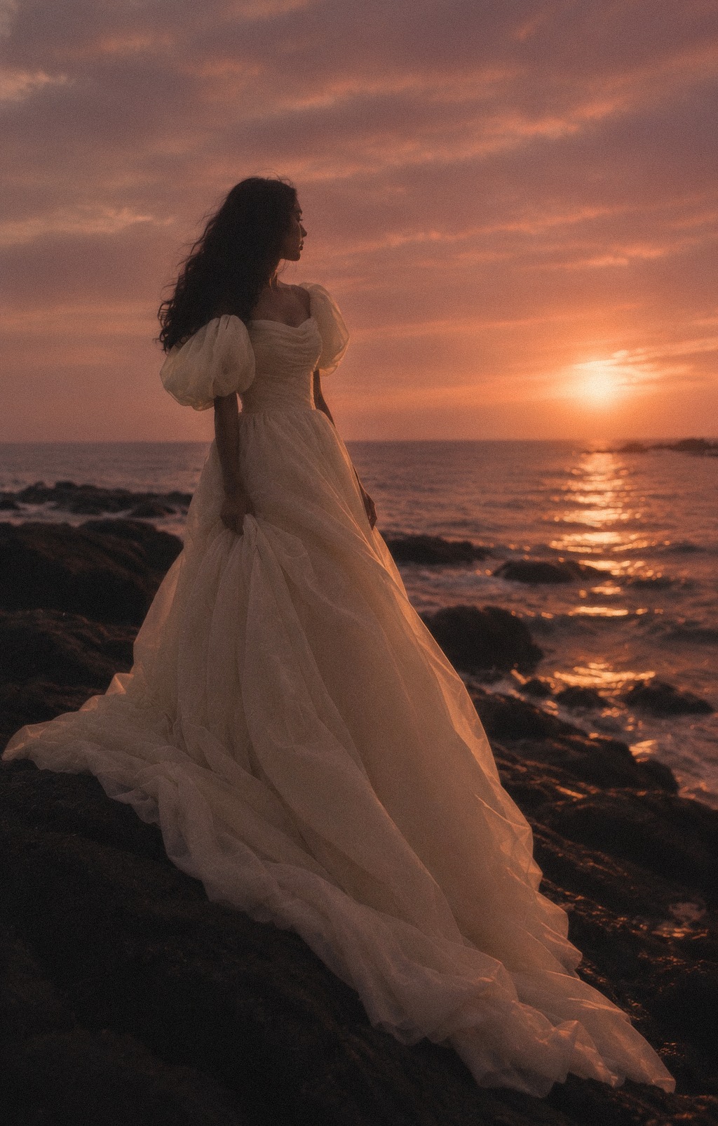 Bride in an organza gown against a coastal sunset